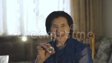 一位微笑的老妇人手持一<strong>枚</strong>银币在镜头前的画像
